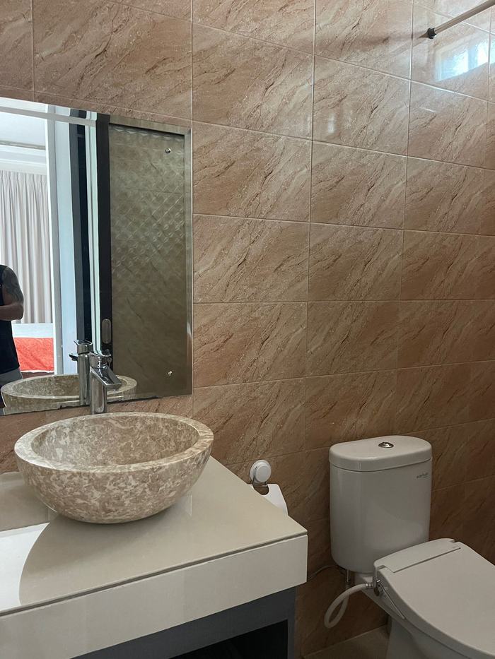 Bathroom with stone vessel sink, warm tile, and natural light