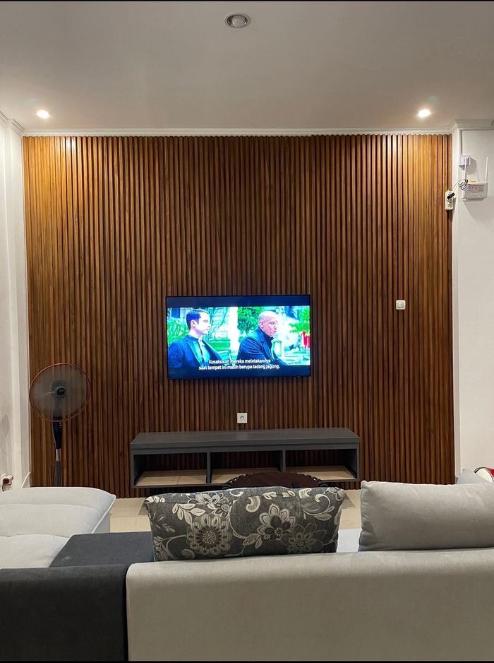 Living room with smart TV mounted on teak slats and modular sofa